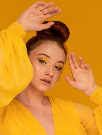 Gorgeous ginger woman in yellow dress looking at the camera. Female bright look. Colorful background and makeup. A lot of copy space.の写真素材