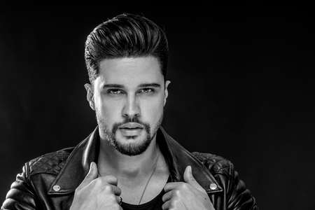 Portrait of a handsome young man with manly face. Male beauty. Fashionable brunet guy in black leather jacket looking at the camera. A lot of copy space.の写真素材
