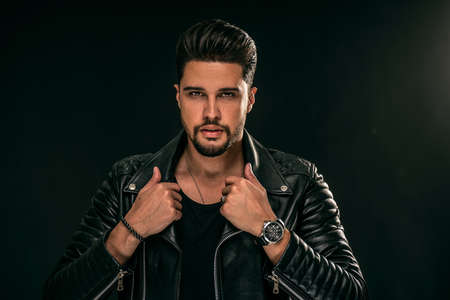 Portrait of a handsome young man with manly face. Male beauty. Fashionable brunet guy in black leather jacket looking at the camera. A lot of copy space.の写真素材