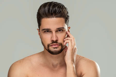 Handsome bearded brunet man posing shirtlesss, looking at the camera. Male's beauty, skincare concept. A lot of copy space.の写真素材