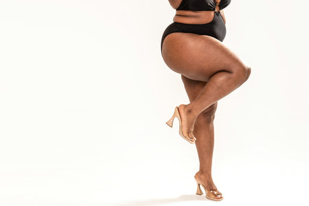 Real body of plus size African woman. Concept of body acceptance, body positivity. Legs with fashionable high heels. A lot of copy space. Love yourself.の写真素材