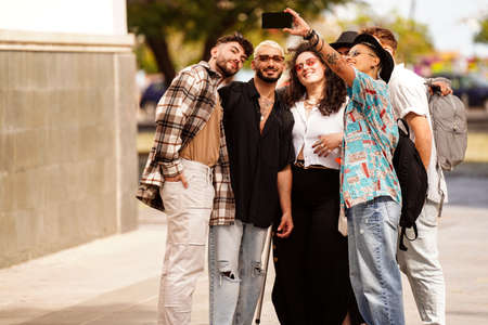 Group of young fashionable friends taking selfie at the city walk, smiling and having fun. Outdoor photo. Real people lifestyle. Happy students.の写真素材