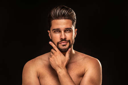 Handsome sensual man with brown eyes posing shirtless on black studio background. Copy space. Muscular body.の写真素材
