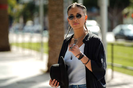 Portrait of pretty young hipster woman on the city walk. Fashionable girl wearing jewelry and sunglasses.の写真素材