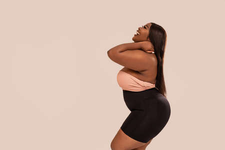 Happy, attractive, plus size, dark skinned woman smiling, posing in studio. Beauty portrait. Concept of body acceptance, body positivity. Girl power.の写真素材