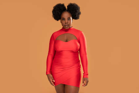 Beautiful african Woman posing in red mini dress, looking at the camera. Afro hairstyle, glamor makeup. Studio Background. Fashionable girl. A lot of copy space.の写真素材