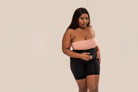 Attractive, plus size, dark skinned woman looking at the camera, posing in studio. Concept of body acceptance, body positivity. Girl power.の写真素材