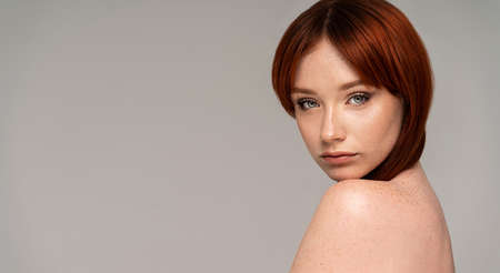 Natural young redhead woman with beauty face and freckles. Healthy facial skin care. Beautiful girl with delicate makeup, red hair looking at the camera. Copy space.の写真素材