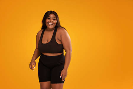 Happy plus size woman posing in sporty black fashionable clothes, smiling to the camera. Copy space....