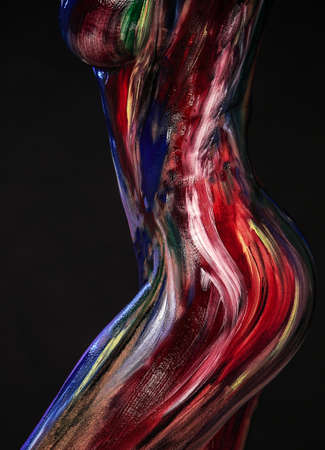 Body part art. Photo of female sensual creative body in colorful paints on a black studio background. A lot of copy space.の写真素材