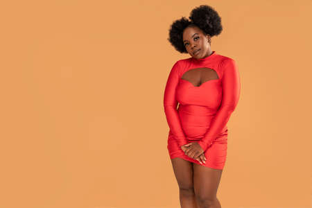 Beautiful african Woman posing in red mini dress, looking at the camera. Afro hairstyle, glamor makeup. Studio Background. Fashionable girl. A lot of copy space.の写真素材