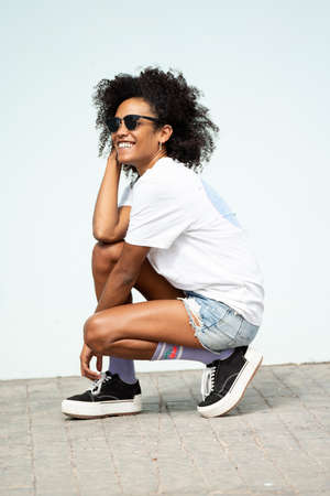Happy young hipster woman with afro hairstyle and fashionable clothes posing outdoor. Sunny summer day. Good vibes only.の写真素材
