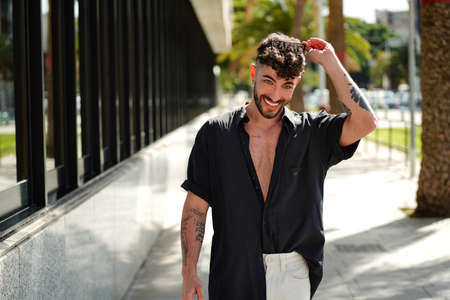 Photo of happy young man in casual shirt looking at camera. Smiling man with beard on the city street. Tourist.の写真素材
