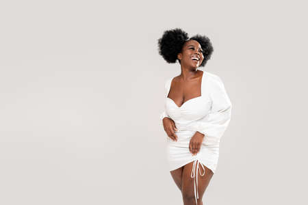 Very happy young woman in fashionable, white mini dress. Real excited, winner expression, big smile. People emotions. Copy space. Studio shot. Girl with afro hairstyle.の写真素材