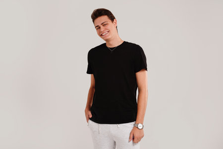 Handsome young happy man posing in black fashionable shirt, smiling and looking at the camera....