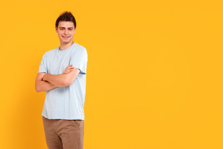 Studio photo of young handsome boy in casual style clothes, looking at camera with smile, isolated over yellow studio background. Real people emotions, youth, fashion concept. Copy space.の写真素材