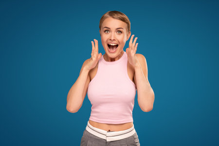 Young emotional surprised woman looking at the camera, posing on blue studio background. Human emotions, facial expression concept. Trendy colors. Wow. Sale.の写真素材