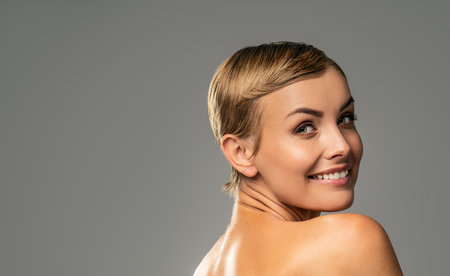 Beauty portrait of caucasian attractive woman with blonde short hair and amazing smile. Natural, delicate makeup. Fashionable haircut. Girl looking at the camera. Studio background.の写真素材