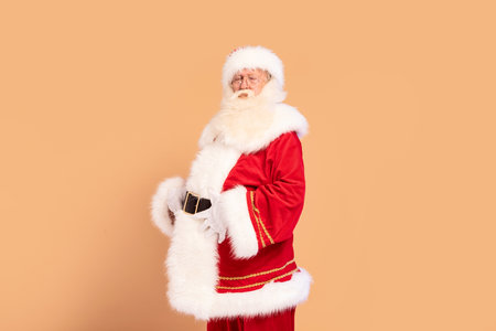 Hungry Santa Claus is ready for all the xmas cookies. Merry Christmas and Happy New Year. A lot of copy space on the beige studio background.の写真素材