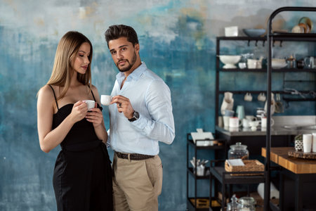 Handsome happy couple drink coffee in the morning in kitchen at home. Romantic relationship.の写真素材
