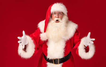 Photo of real, happy Santa Claus annoucing big xmas sale on a red studio background. Merry Christmas and Happy New Year!の写真素材