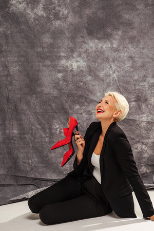 Happy stylish woman with short blonde hairstyle and glamour makeup looking and smiling to the camera, relaxing after work. Elegant businesswoman. Studio shot. Copy space.の写真素材