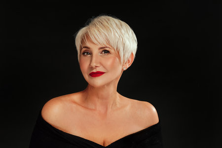 Beauty portrait of elegant woman with short blonde hairstyle and glamour makeup with red lips posing on black studio background.の写真素材