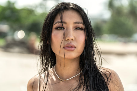 Beauty portrait of natural, attractive, young asian woman with wet hair and delicate makeup. Girl looking at the camera. skincare. tan. Beach sunny day on the island.の写真素材