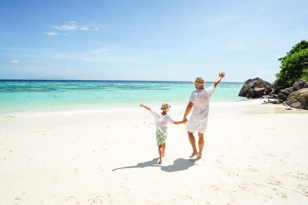 Happy family , dad and son, having fun together at the tropical beach, playing and looking at the blue sea and sky. Summer vibes. island life. tourists.の写真素材