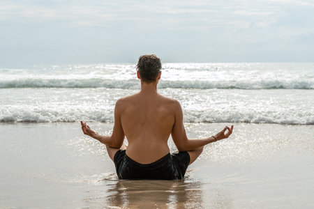Man practicing yoga and meditates on the beach, ocean view. Relax, freedom. Healthy lifestyle. Wanderlust. Traveler.の写真素材