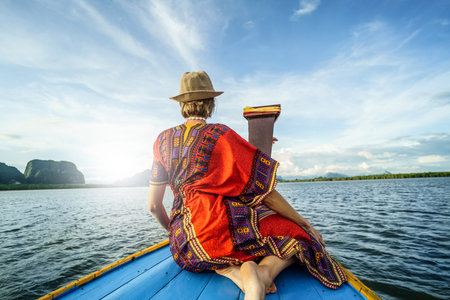 Travel tour by traditional long tail boat on tropical islands in Thailand. Woman sitting and relaxing, looking at the landscape. Summer exotic holidays in Asia.の写真素材