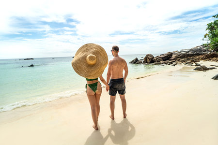 Back view of fit couple watching seascape on the beach, holding hands. People from behind relaxing, enjoying summer travel vacation on tropical island. tourism. Travelers. love.の写真素材