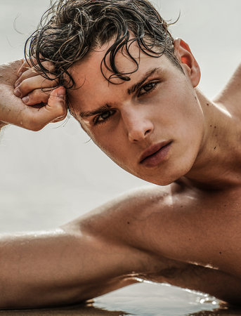Beauty closeup portrait of handsome young man. Boy looking at the camera, relaxing on the beach. small model.の写真素材