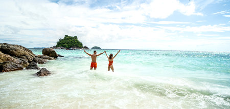 Happy couple having fun on the tropical beach, standing in the water, relaxing, sunbathing. back view. copy space. Travelers. tourists. Nature. Island vibes.の写真素材
