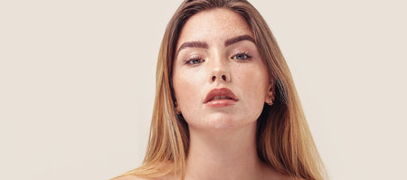 Studio beauty portrait of young natural woman with freckles on her face. Girl looking at the camera. A lot of copy space. skincare concept. Ideal, delicate makeup with lipstick.の写真素材