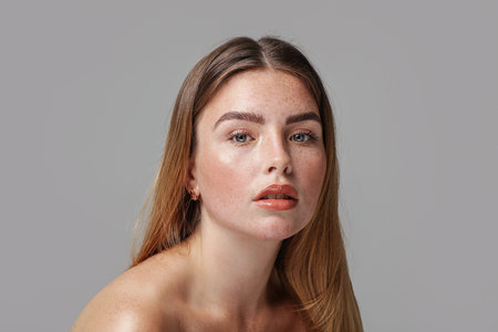 Studio beauty portrait of a very natural woman with freckles on her face. Girl looking at the camera. A lot of copy space. skincare concept. Ideal, delicate makeup.の写真素材