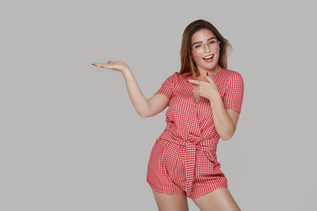 Studio photo of cheerful attractive young woman with big smile pointing on empty place. Commercial promo area.の写真素材