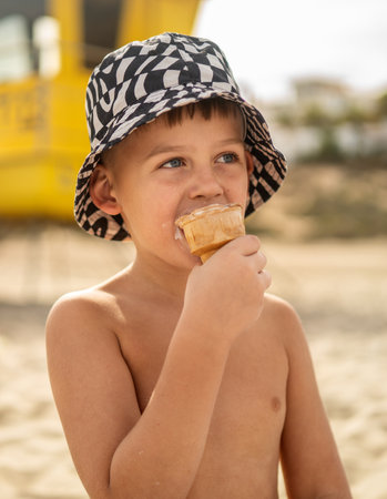 Happy child eating ice cream outdoors in summer, enjoying sunny day. Portrait of a small boy at vacation.の写真素材
