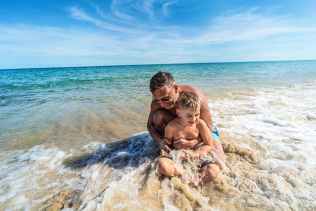 Smiling m and kid boy having fun together at the ocean. Dad with son playing on the beach. Summer activities. Real people lifestyle. tourism.の写真素材