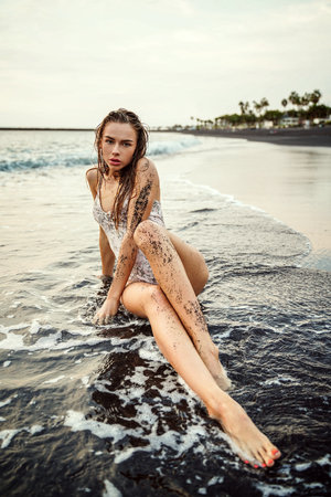 Sensual woman in white swimwear posing on tropical beach. Portrait of a beautiful young woman enjoying the sea shore. sexy girl. sunset light.の写真素材