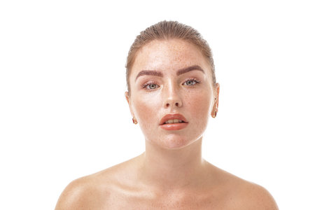 Studio beauty portrait of very natural woman with freckles on her face and shoulders. Girl looking at the camera. A lot of copy space. Skin care concept. Ideal, delicate makeup.の写真素材