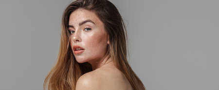 Studio beauty portrait of very natural woman with freckles on her face and shoulder. Girl looking at the camera. A lot of copy space. Skin care concept. Ideal, delicate makeup.の写真素材