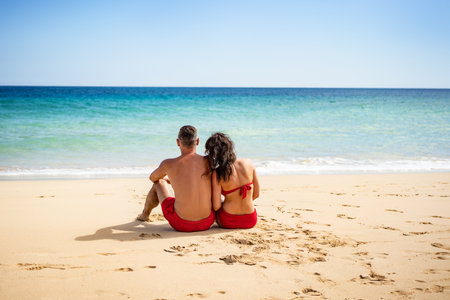 Beautiful couple watching blue sea together on the sandy beach, travel summer holidays. Tropical destination , vacation.の写真素材