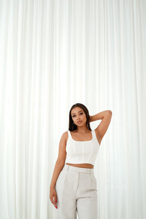 Attractive young woman posing on white curtains. Casual, fashionable mixed-race girl Gorgeous model looking at camera. A lot of copy space.の写真素材
