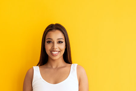 Happy young woman smiling. Beauty female portrait. Real human emotions, facial expression concept. A lot of copy space. Yellow studio background.の写真素材