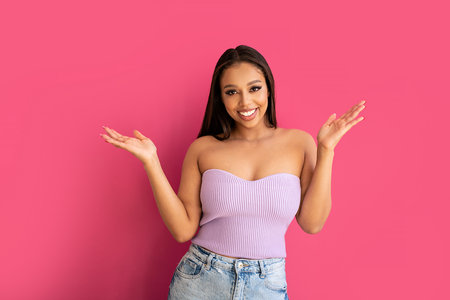 Joyful woman laughing, looking at the camera, posing on a pastel pink Studio Background. Real people emotions, toothy smile. Fashionable young girl in violet top and jeans.. A lot of copy space.の写真素材