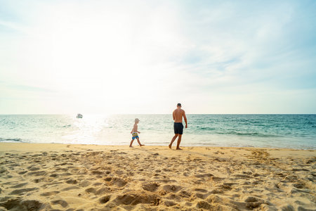 Father and son walking on summer beach. Dad and child having fun outdoors. Family travel, vacation, fathers day concept.の写真素材