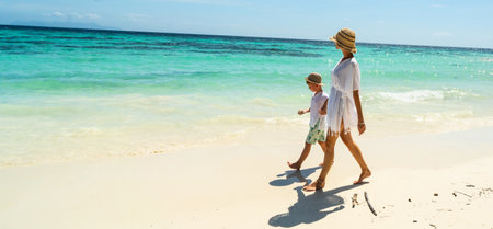 Happy mother and son walking, relaxing on the tropical sandy beach, Enjoying life. Summer day. Vacation. Travel.の写真素材