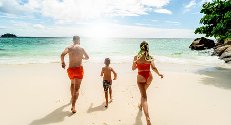 Tropical summer vacations. Happy family having fun together on the beach. Father, mother, son running. Thailand, Koh Lipe.の写真素材