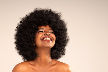 Studio portrait of young happy woman with afro hair and amazing toothy smile . Joyful girl posing in studio, expressing happiness and good mood. Happiness and real positive emotions.の写真素材